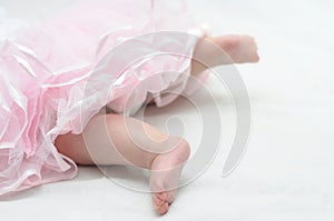 Foots of newborn baby in pink dress dancing