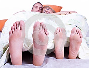 Foots of young couple lying in bed photo