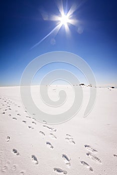 Footstep trails at snow by sunny day