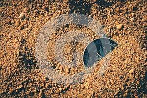 Footsteps in the sand lead to a compass, guiding the travel