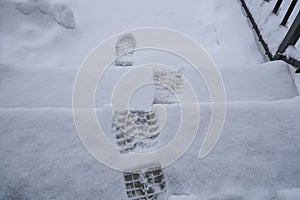 Footsteps in snow on staircase close-up top view. Winter season. natural background