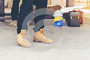 Footwear concept.Handsome man wear jeans knelt down to do up his shoelaces. Preparing before go to party. Brown boots on green