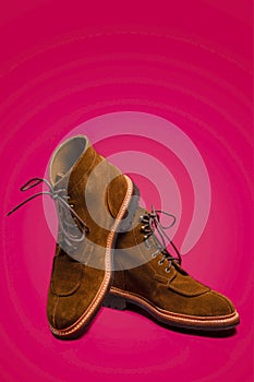 Footwear Concept. Pair of Tan Brown Suede Split Toe High Boots Close - up With Heavy Rubber Sole Placed on One Another Over Pink
