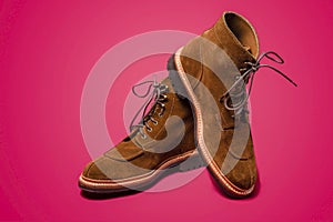 Footwear Concepts. Pair of Tan Brown Suede Split Toe High Boots Closeup With Rubber Sole Placed on One Another Over Pink Red