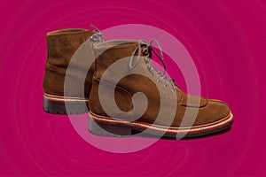 Footwear Concepts. Tan Brown Suede Split Toe High Boots Closeup With Visible Leather Texture Placed Over Pink Red Background