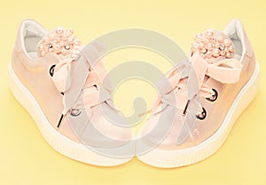 Footwear for girls or women decorated with pearl beads. Glamorous footwear concept. Pair of pale pink female sneakers