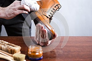 Footwear Ideas and Concepts. Extreme Close Up of Mans Hands Cleaning Luxury Calf Leather Brogues with Special Cloth