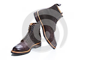 Footwear Ideas. Premium Dark Brown Grain Brogue Derby Boots Made of Calf Leather with Rubber Sole Placed on One Another Over White