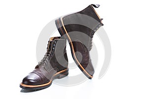 Footwear Ideas. Premium Dark Brown Grain Brogue Derby Boots Made of Calf Leather with Rubber Sole Placed on One Another Over White