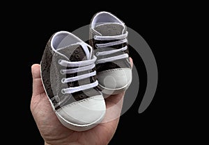 Footwear for the smallest children. Slippers for babies in hand. Children`s shoes of small size,  on black