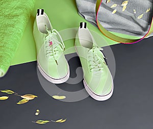 Footwear for women green   sneakers  towel and handbag for relaxation time on green and grey  background