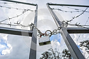 Forbidden area fenced with a barbed wire fence. Gate with padlock closed to the key. Border of States