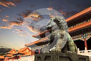 León de bronce en la ciudad prohibida con el resplandor de la puesta de sol en beijing, China.