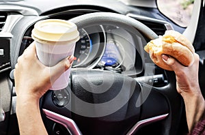 forbidden and perilous with close-up of woman's hand, holding burger and coffee, While driving photo