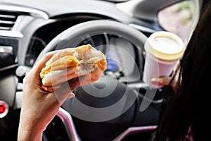 forbidden and perilous with close-up of woman\'s hand, holding burger and coffee, While driving photo