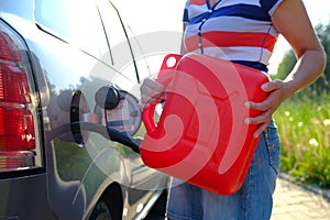 Forced stop. Ran out of gas in the tank of the car. A woman fills the car with gasoline from a spare tank. Canister of 10 liters