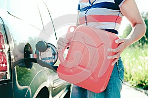 Forced stop. Ran out of gas in the tank of the car. A woman fills the car with gasoline from a spare tank. Canister of 10 liters