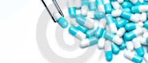 Forceps pick white-blue capsule from group of capsule pills. Drugs choose. Antibiotic drug selection. Antibiotic drug resistance