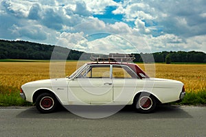 Ford Taunus youngtimer with roof rack and case in front of a corn field