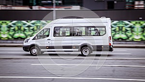 Ford Transit Fourth generation in the city street. Side view of white urban public transit minibus