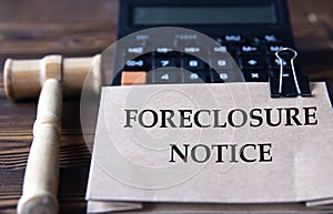 FORECLOSURE NOTICE - words on light brown paper against the background of a calculator and a judge\'s gavel