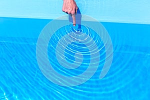 Forefinger making waves as circles in swimming pool