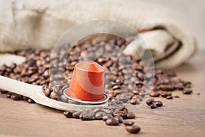 In the forground Wooden spoon and coffee capsule