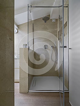 Foreground the masonry shower box with glass door in the modern bathrrom the walls are coated of marble