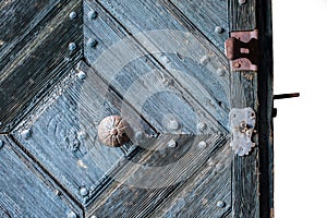 Foreground of old wooden door with iron handle.