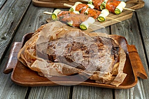 In the foreground is a piece of bacon. Salmon skewer on wooden boards, over wooden vintage background.