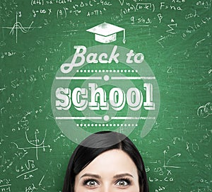 A forehead of the girl and words: ' back to school ' which are written on the green chalkboard.