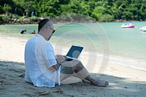 Foreign tourists stroll along Asia\'s beautiful blue sea beaches. Chat on the laptop