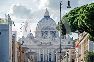 Foreign tourists strolling and being photographed in Rome, Italy on a bright sunny day in front of the dome of the main Catholic c