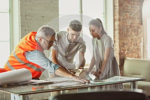 Foreman or achitect shows house, office or store design plans to a young couple photo