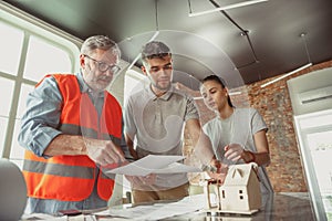 Foreman or achitect shows house, office or store design plans to a young couple