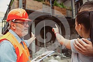 Foreman or achitect shows house, office or store design plans to a young couple