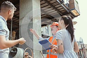 Foreman or achitect shows house, office or store design plans to a young couple