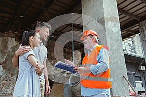 Foreman or achitect shows house, office or store design plans to a young couple