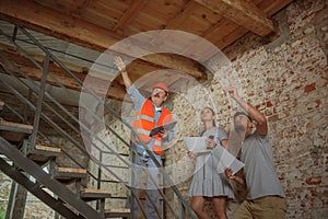 Foreman or achitect shows house, office or store design plans to a young couple