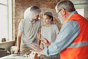 Foreman or achitect shows house, office or store design plans to a young couple photo