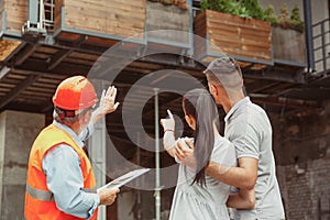 Foreman or achitect shows house, office or store design plans to a young couple photo