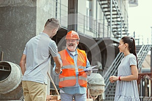 Foreman or achitect shows house, office or store design plans to a young couple photo