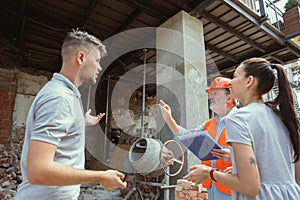 Foreman or achitect shows house, office or store design plans to a young couple photo