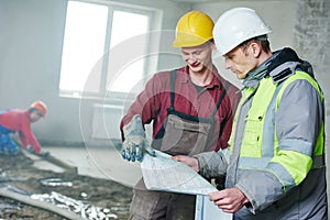 Foreman builder and construction worker with blueprint in indoor apartment