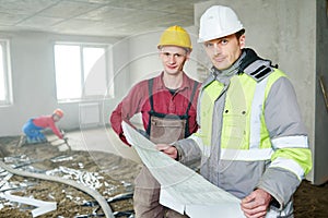 Foreman builder and construction worker with blueprint in indoor apartment