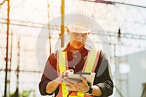 Foreman builder engineer worker using tablet computer to check building floor plan at construction site