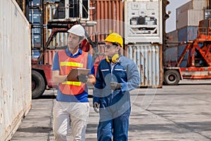 Foreman and cargo container worker walk and discuss together for checking product in workplace area. Business Logistics import