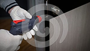 The foreman carries out repair work in the apartment  drills the door lock  the man repairs the interior door.