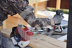 The foreman checks the work of the gasoline trimmer after winter storage, background