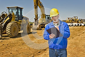 Foreman With Clipboard and Highway Construction Equipment